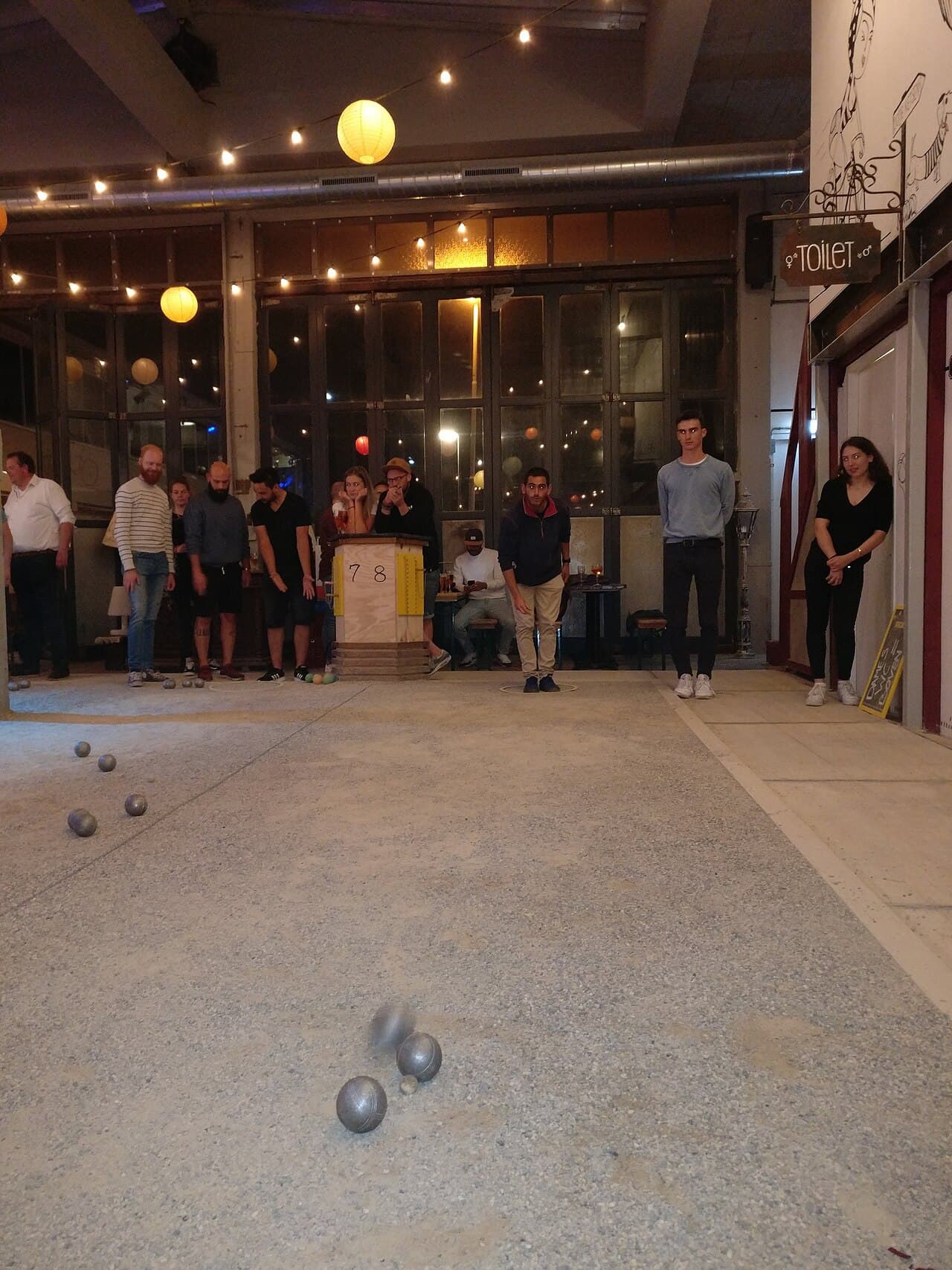Groep speelt jeu de boules binnen in een hal met lampjes
