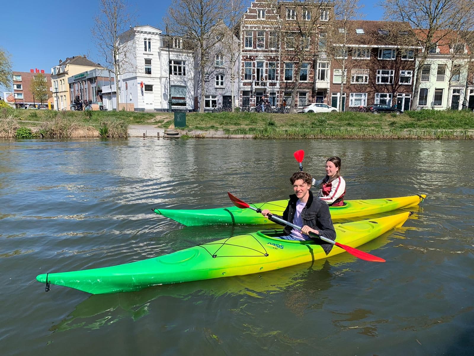 Twee personen in een groene kano op de gracht